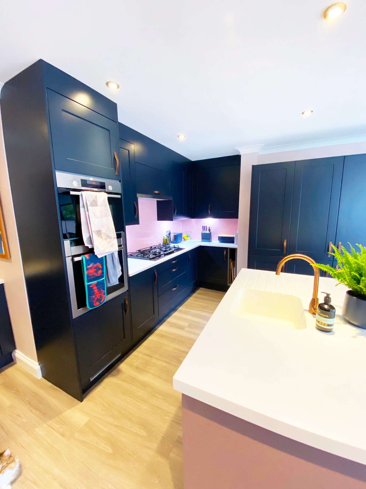 Brass tap and sink in a white quartz island facing indigo units