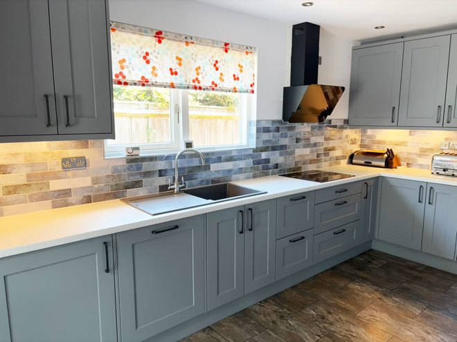 Dust grey shaker kitchen with brick-style wall tiles and a black cooker hood