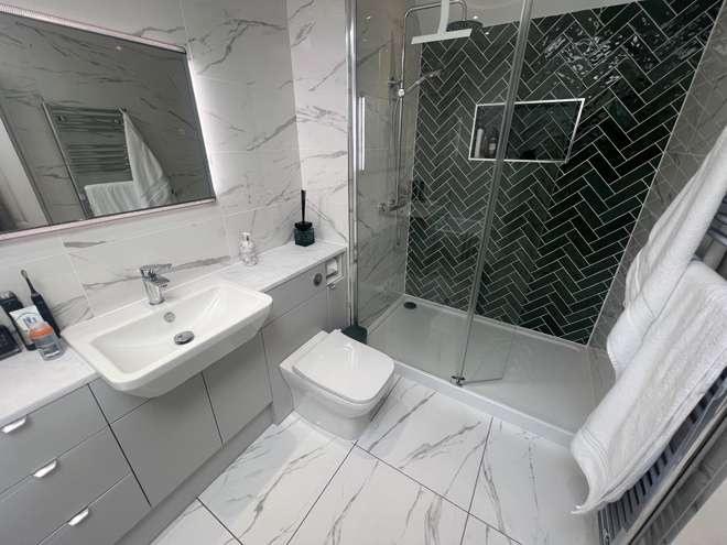 En suite with Grey Mist units, marble-effect tiles and a green herringbone shower wall