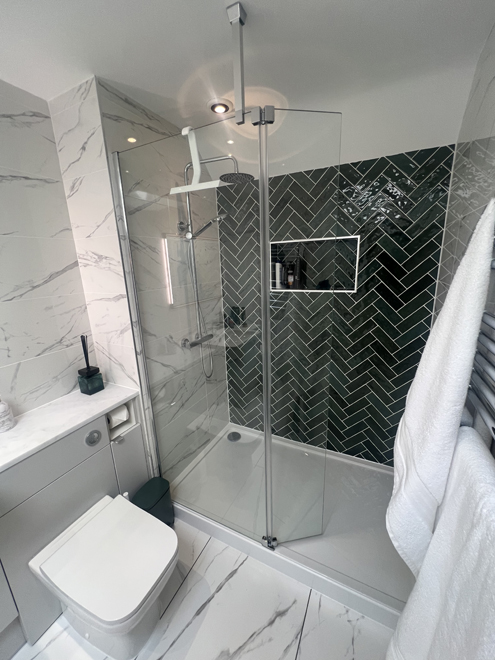 Walk-in shower with a green herringbone feature wall