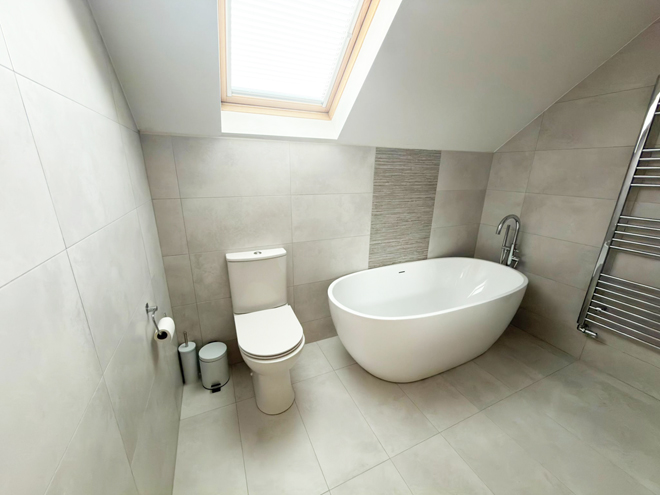 Freestanding bath under a sloping ceiling with a floor-standing mixer