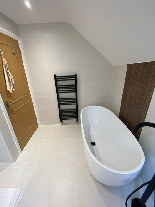 Freestanding bath beside a black towel warmer